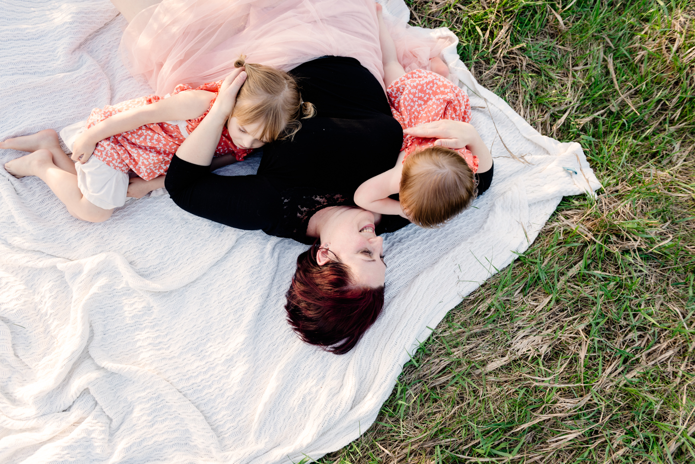 photograph of mom laying on blanket with daughters