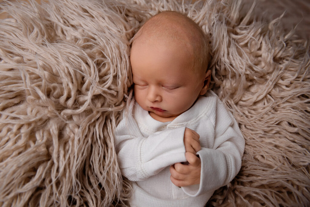 Baby girl posed safely in soft pink newborn setup photographed by Alabaster Photos