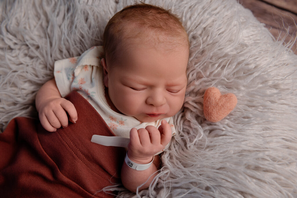 Newborn photographer in New Richmond WI gently posing sleepy baby in neutral studio setup at The Croix Studio