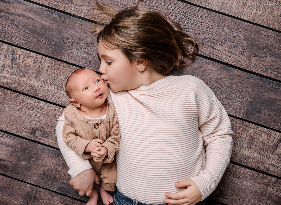 Overhead view of baby resting in sisters arms, storytelling newborn photography St. Croix Valley